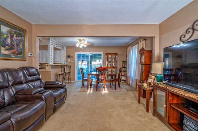 living room with a textured ceiling, light colored carpet, and ceiling fan