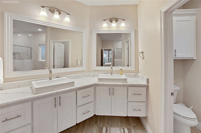 6701 Paddington Dr, Corpus Christi, TX 78414 - bathroom with double vanity, a sink, toilet, and wood finished floors