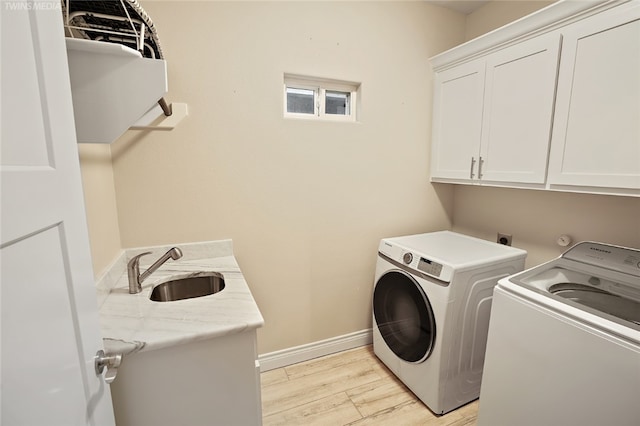 6701 Paddington Dr, Corpus Christi, TX 78414 - laundry room with baseboards, a sink, independent washer and dryer, cabinet space, and light wood-style flooring