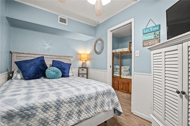 bedroom with ceiling fan, a textured ceiling, and light wood-type flooring