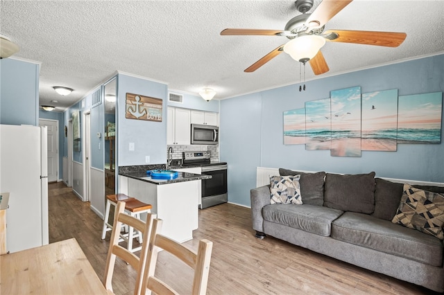 kitchen featuring white cabinetry, appliances with stainless steel finishes, kitchen peninsula, light hardwood / wood-style floors, and decorative backsplash