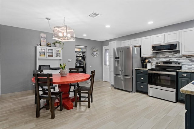 kitchen with visible vents, stainless steel appliances, white cabinetry, and pendant lighting