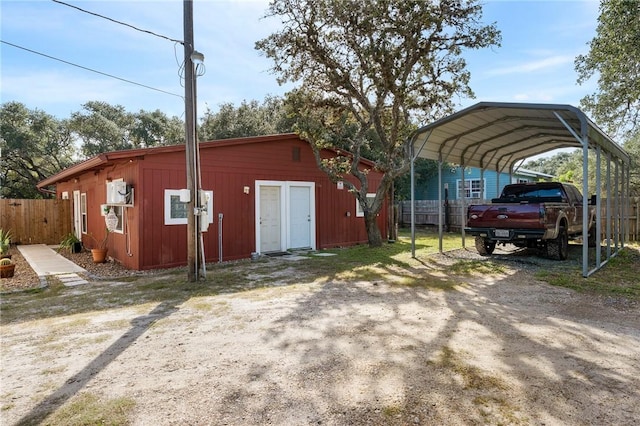 view of outdoor structure featuring fence, driveway, an outdoor structure, and a detached carport