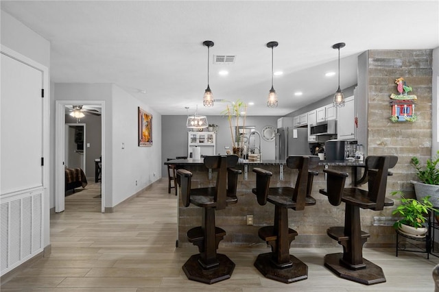 kitchen featuring visible vents, white cabinets, decorative light fixtures, and appliances with stainless steel finishes