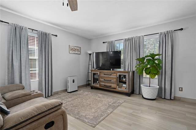 living room with ceiling fan, light wood finished floors, and baseboards