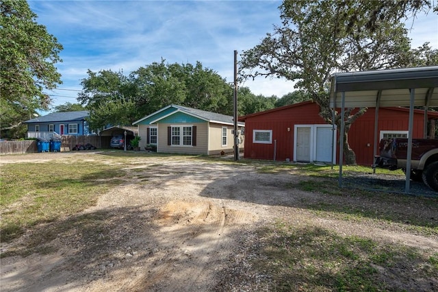 view of front facade with an outdoor structure, dirt driveway, and a carport