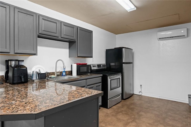 kitchen with a sink, a wall unit AC, gray cabinetry, tile countertops, and stainless steel appliances