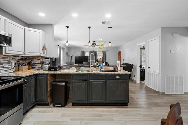 kitchen featuring light stone counters, visible vents, white cabinets, and appliances with stainless steel finishes