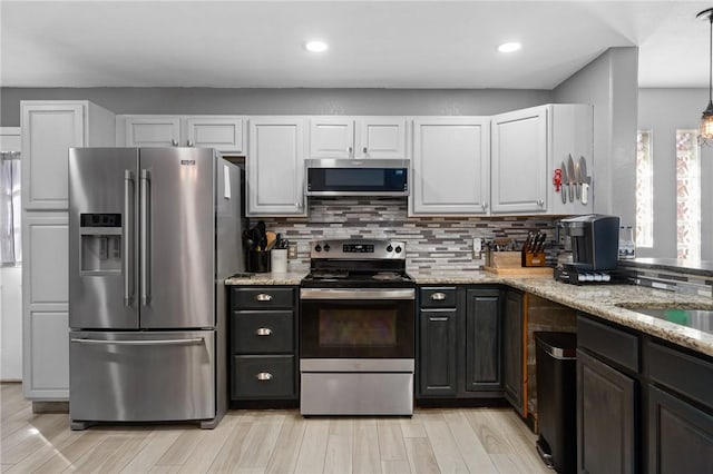 kitchen featuring white cabinetry, appliances with stainless steel finishes, light stone countertops, and backsplash