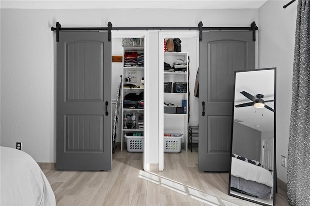 bedroom featuring light wood finished floors and a barn door