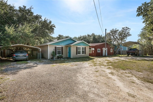 view of front of house with fence, dirt driveway, and a detached carport