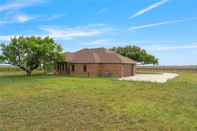 back of property featuring central AC unit, fence, brick siding, a garage, and a lawn