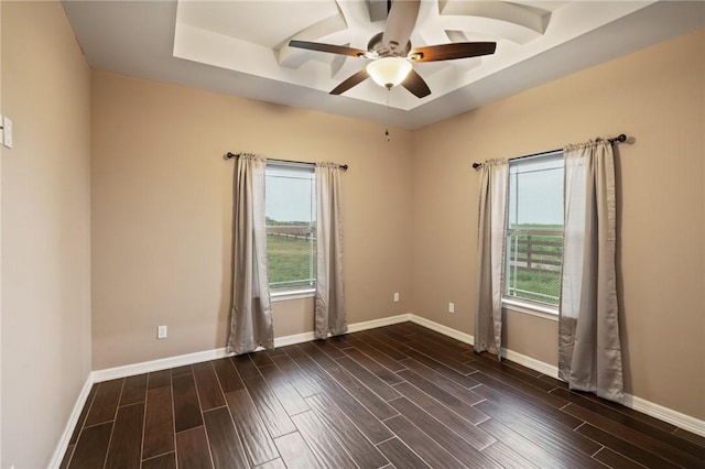 spare room featuring a tray ceiling, baseboards, dark wood-style floors, and ceiling fan