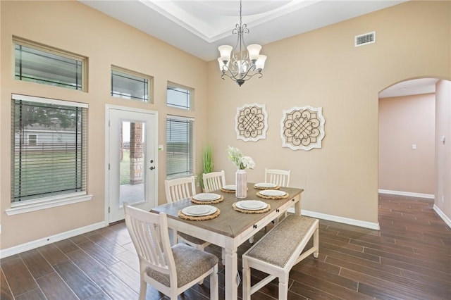 dining area with arched walkways, baseboards, visible vents, a notable chandelier, and dark wood-type flooring