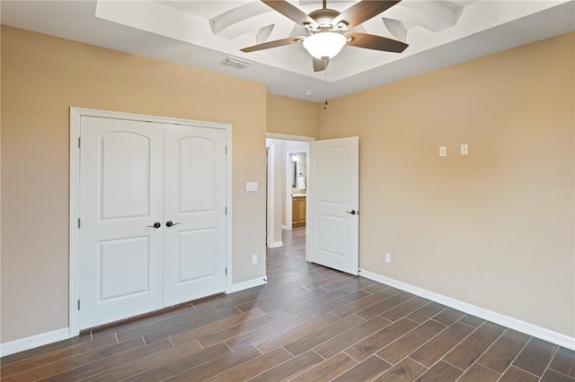 unfurnished bedroom with a closet, ceiling fan, dark wood finished floors, baseboards, and visible vents