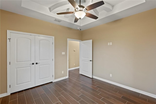 unfurnished bedroom featuring baseboards, visible vents, a raised ceiling, and dark wood-style flooring
