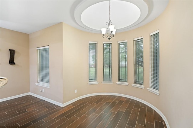 unfurnished dining area with baseboards, an inviting chandelier, and dark wood finished floors