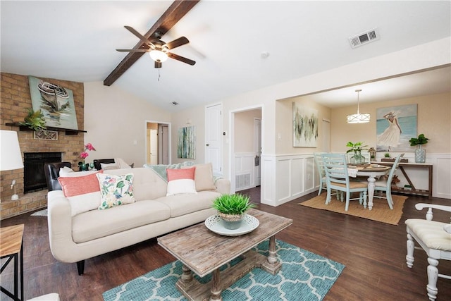 living room with visible vents, dark wood finished floors, wainscoting, lofted ceiling with beams, and a fireplace