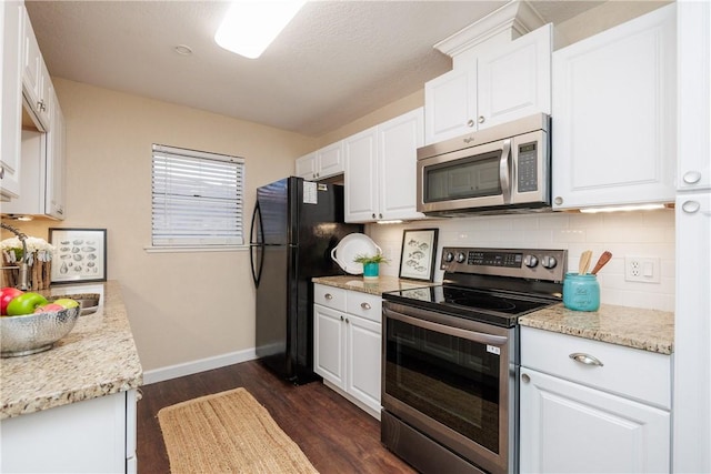 kitchen with dark wood-style flooring, backsplash, appliances with stainless steel finishes, white cabinets, and baseboards