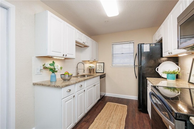 kitchen with light stone countertops, white cabinetry, appliances with stainless steel finishes, and a sink