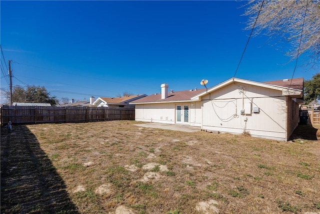 back of house with a patio area, a fenced backyard, a lawn, and french doors