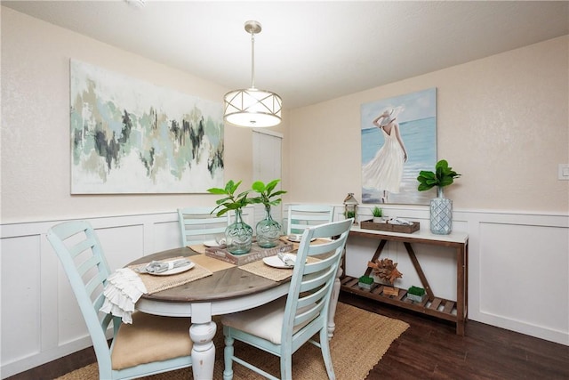 dining area with a wainscoted wall, wood finished floors, and a decorative wall