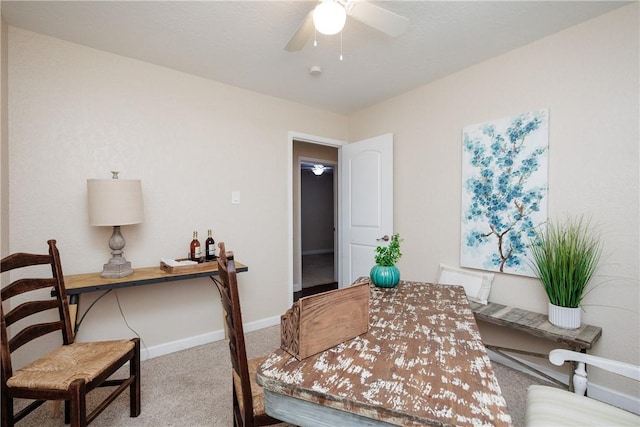 carpeted office space with baseboards and a ceiling fan