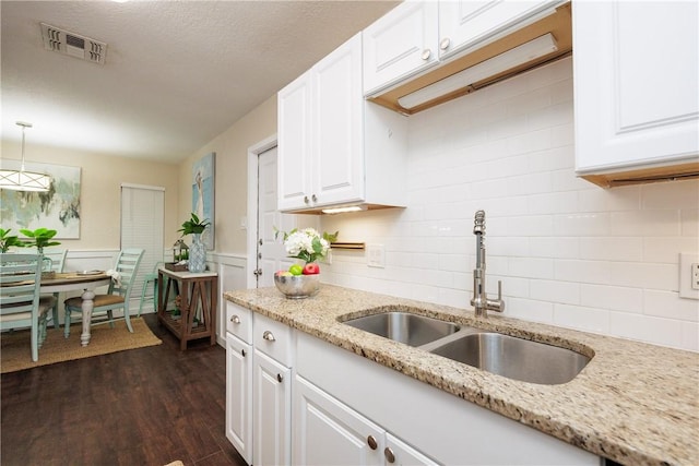 kitchen featuring dark wood-style flooring, visible vents, a sink, and white cabinets