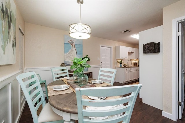 dining space with dark wood-style floors, wainscoting, and visible vents