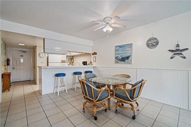 14810 Windward Dr Unit 301, Corpus Christi, TX 78418 - dining space featuring ceiling fan, light tile patterned flooring, a textured ceiling, and a wainscoted wall