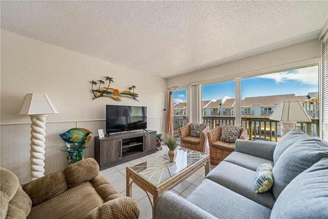 14810 Windward Dr Unit 301, Corpus Christi, TX 78418 - living room featuring light tile patterned floors, a wainscoted wall, and a textured ceiling