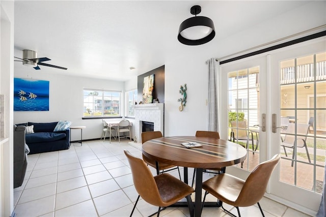 dining area with light tile patterned floors, a fireplace, french doors, and a ceiling fan