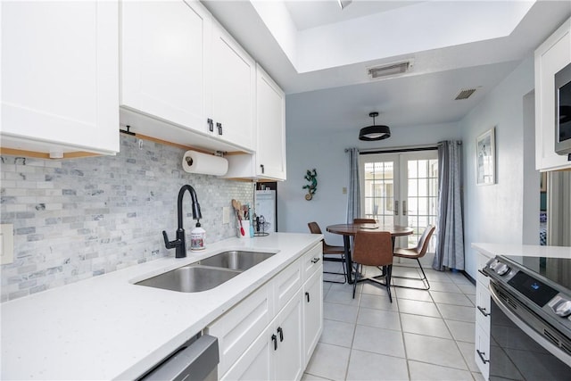 kitchen with stainless steel appliances, a sink, light countertops, white cabinetry, and tasteful backsplash