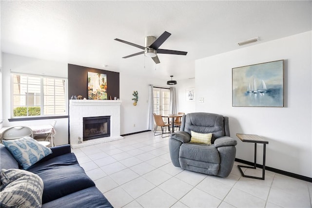 living area featuring visible vents, a ceiling fan, light tile patterned flooring, and a fireplace