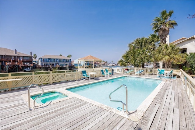 community pool with a community hot tub, fence, and a wooden deck