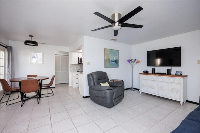 living room with light tile patterned floors, visible vents, baseboards, and ceiling fan