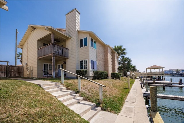 exterior space with fence, a lawn, and a water view