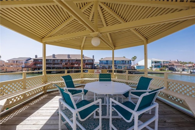 deck with a residential view, outdoor dining area, and a water view