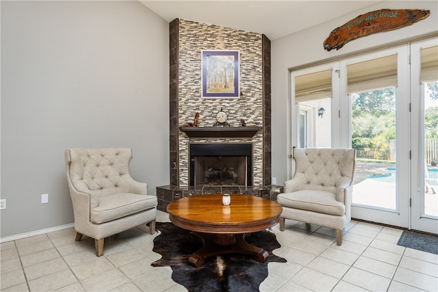 sitting room featuring lofted ceiling, french doors, light tile patterned floors, and a fireplace