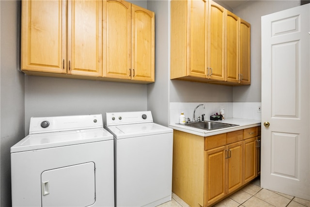 clothes washing area with light tile patterned floors, cabinets, sink, and washer and dryer