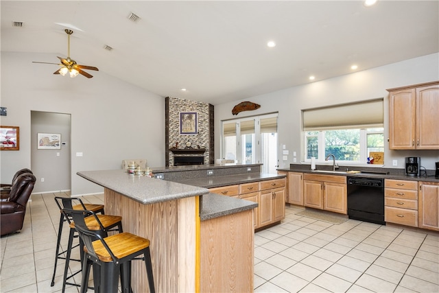 kitchen featuring light brown cabinets, vaulted ceiling, a kitchen bar, and dishwasher