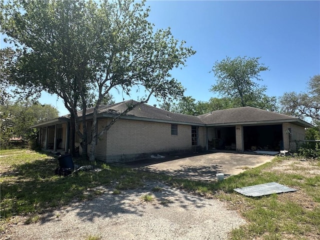 view of front of property featuring a patio, driveway, a garage, and brick siding