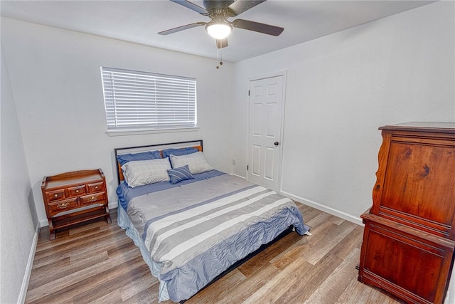 bedroom with wood finished floors, a ceiling fan, and baseboards