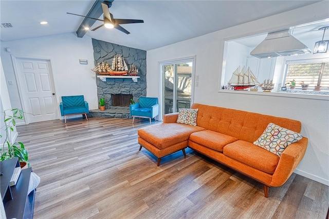 living area featuring a fireplace, visible vents, lofted ceiling with beams, ceiling fan, and wood finished floors