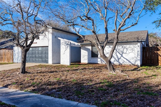 view of front facade featuring a garage, fence, concrete driveway, and brick siding