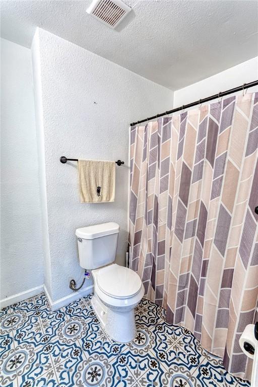 full bath with baseboards, visible vents, toilet, tile patterned floors, and a textured ceiling