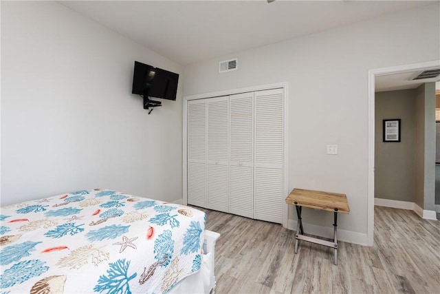 bedroom with light wood-style floors, visible vents, a closet, and baseboards