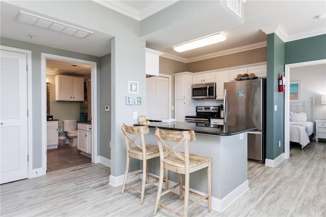 kitchen featuring light wood finished floors, visible vents, stainless steel appliances, and ornamental molding