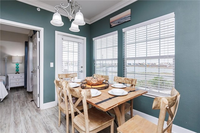 dining space featuring light wood-style floors, baseboards, a notable chandelier, and ornamental molding