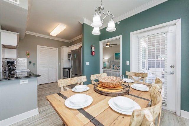 dining space featuring baseboards, ceiling fan with notable chandelier, light wood-type flooring, and ornamental molding